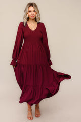 woman wearing a burgundy long sleeve smocked maxi dress with tiered ruffles and a flowy skirt