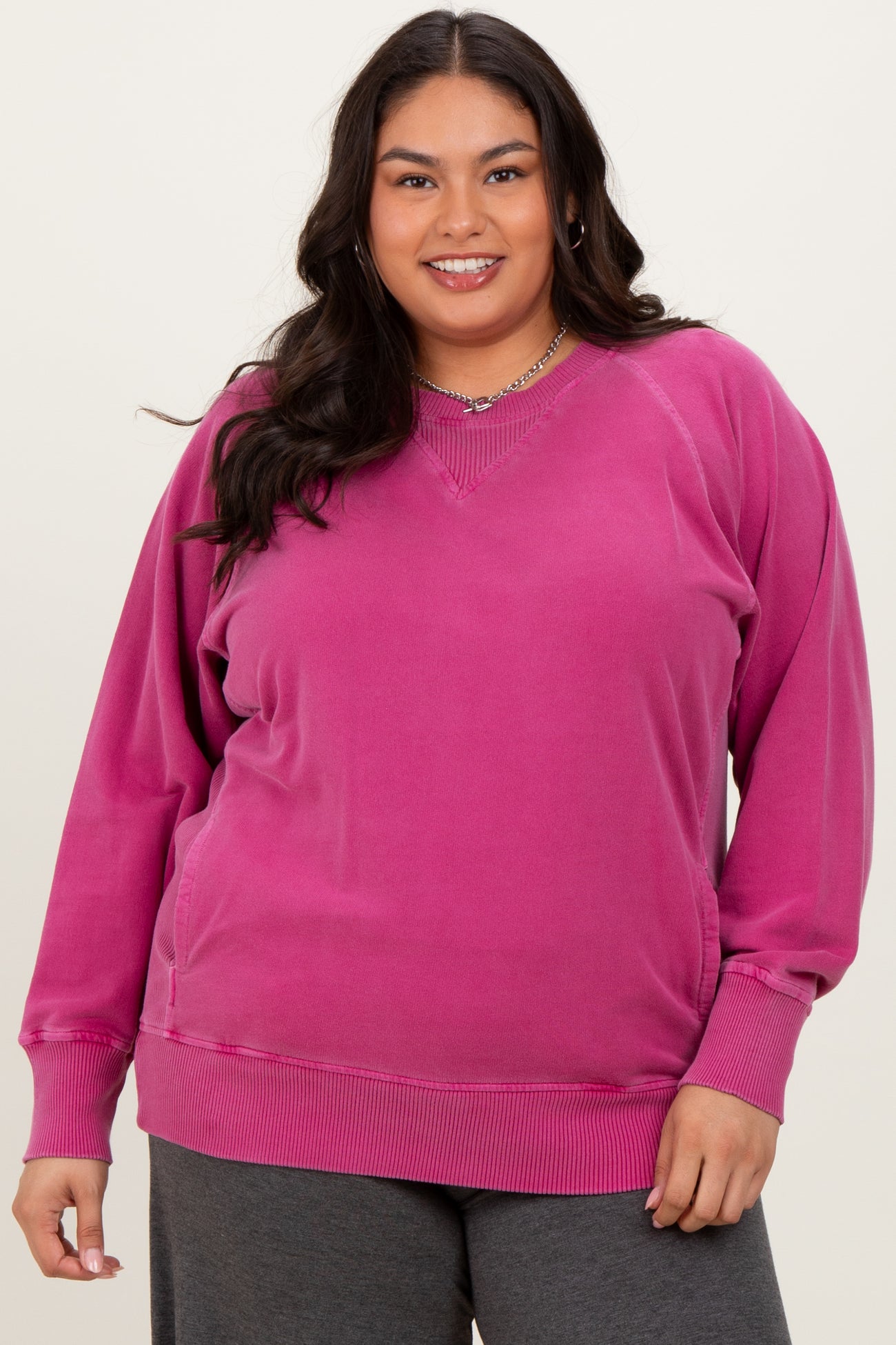 woman wearing a vibrant pink plus size v-neck sweatshirt with long sleeves and relaxed fit