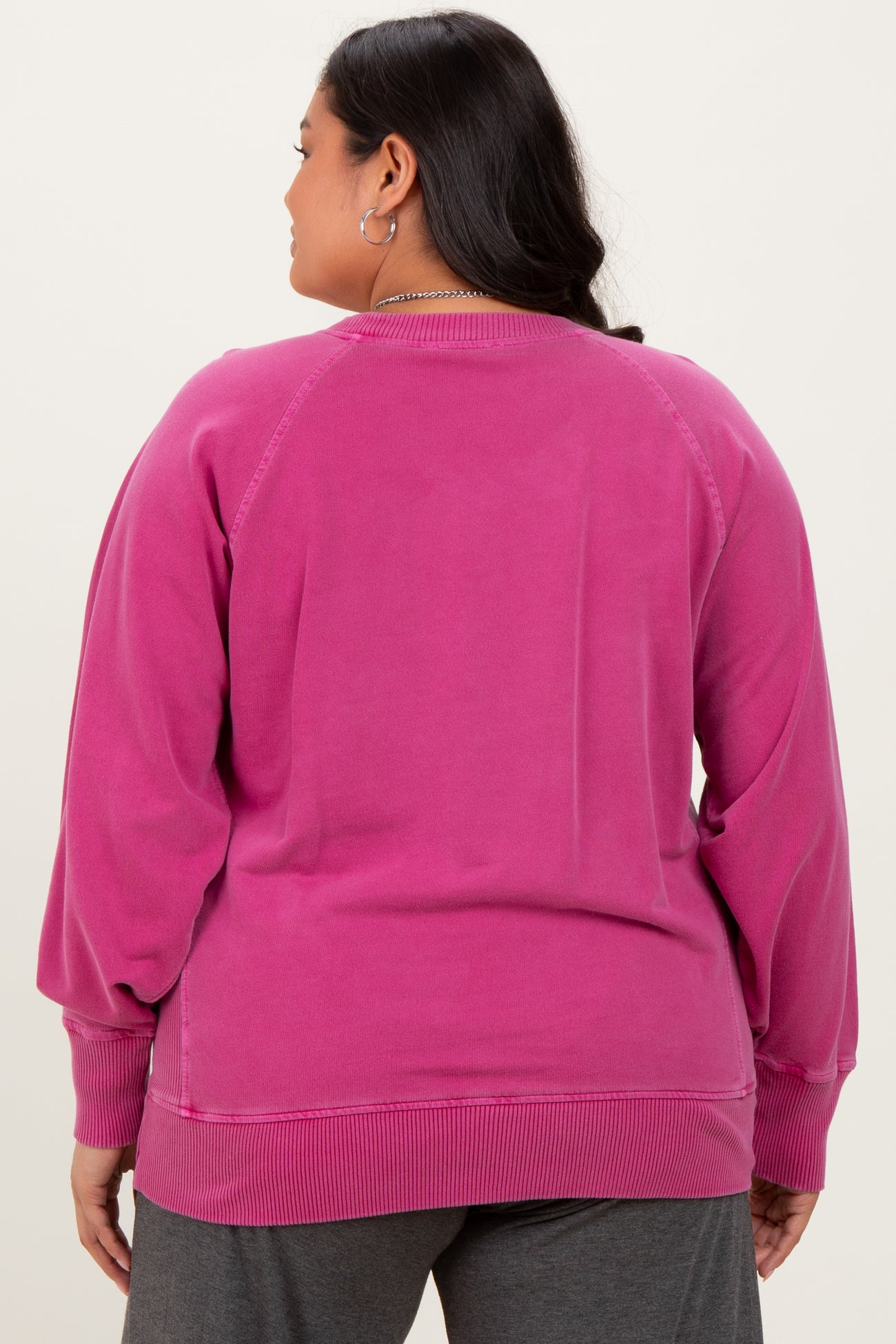 woman wearing a pink plus size sweatshirt with a relaxed fit and ribbed hem, showing the back view