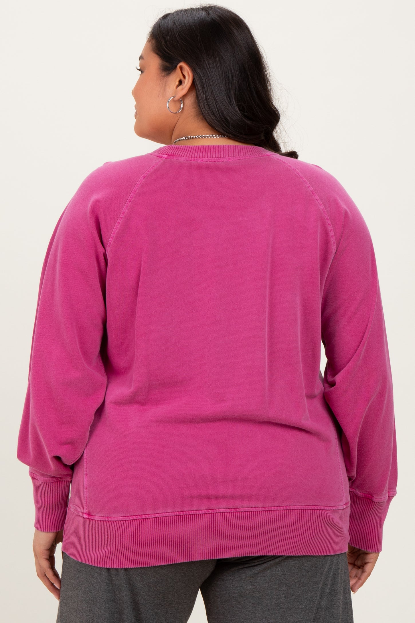 woman wearing a pink plus size sweatshirt with a relaxed fit and ribbed hem, showing the back view