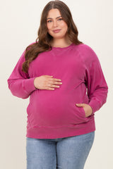 woman wearing a pink maternity sweatshirt with side pockets, showing her baby bump while standing confidently