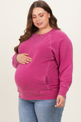 woman wearing a pink maternity sweatshirt and holding her baby bump
