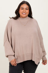 woman wearing a beige oversized ribbed sweater with a high neck and long sleeves, smiling at the camera