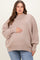 woman wearing a light beige oversized maternity sweater and holding her baby bump