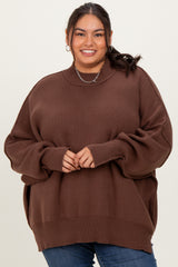 woman wearing a brown oversized ribbed sweater with a high neckline and side slits, styled with blue jeans