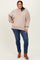 woman wearing a beige oversized sweater with long sleeves paired with blue skinny jeans and brown ankle boots