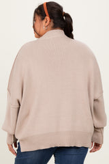 woman wearing a beige oversized sweater with batwing sleeves and a high collar, seen from the back
