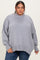woman wearing an oversized light gray sweater with a mock neck and dropped shoulders, paired with blue jeans