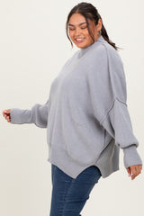 woman wearing a light gray oversized sweater with long sleeves and side slits, paired with blue jeans