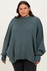 woman wearing a green oversized ribbed sweater with balloon sleeves and a high neckline, paired with black jeans
