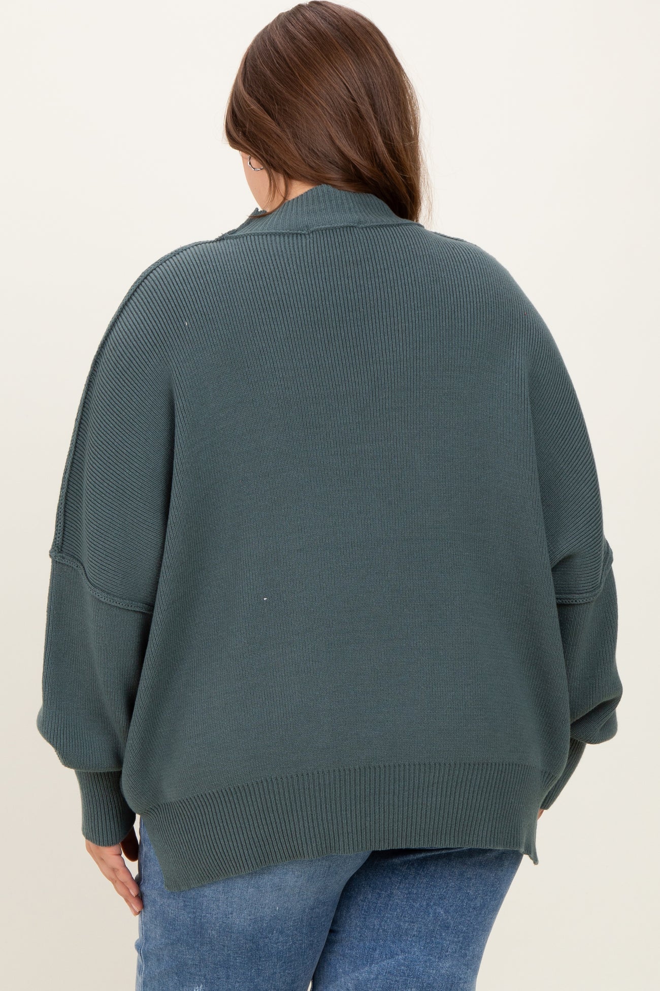 plus size woman wearing an oversized dark green maternity sweater from the back