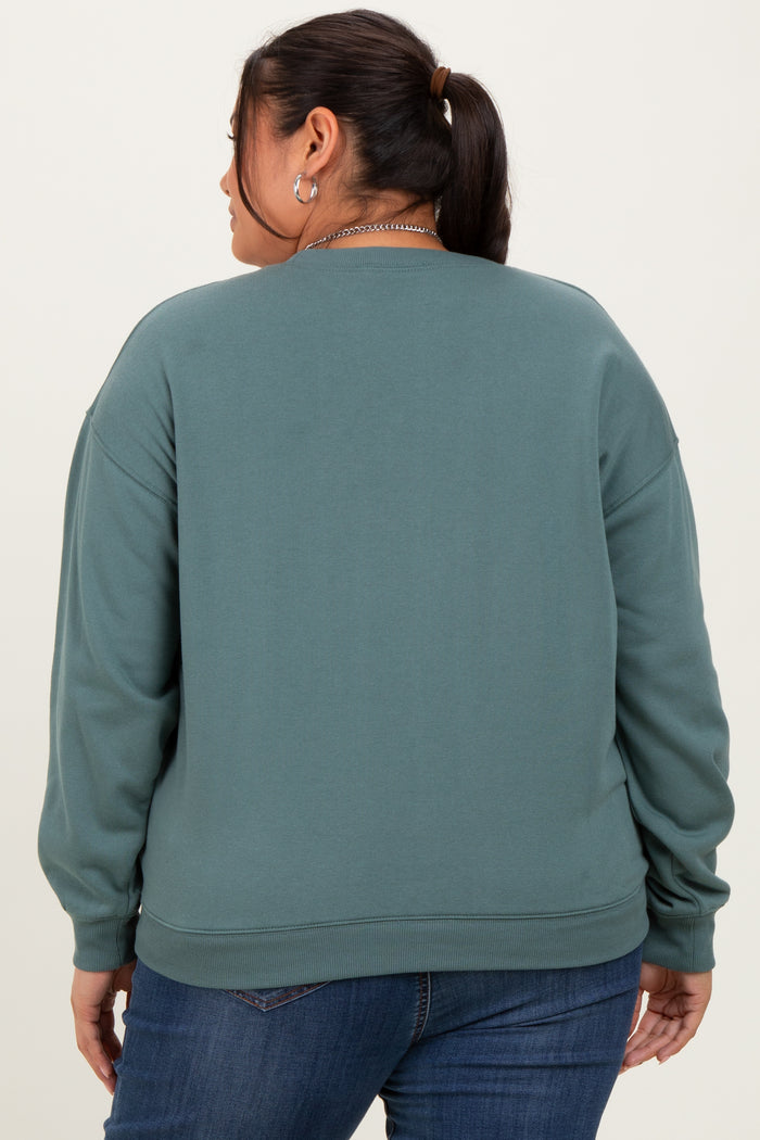 woman wearing a teal oversized sweatshirt with dropped shoulders, viewed from the back, paired with blue jeans