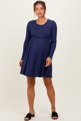 woman wearing a navy ribbed long sleeve maternity dress with a fitted waist and flared skirt, showing her baby bump