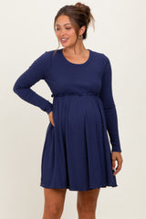 woman wearing a navy blue long sleeve maternity dress with a fitted waist and flared skirt, showing her baby bump