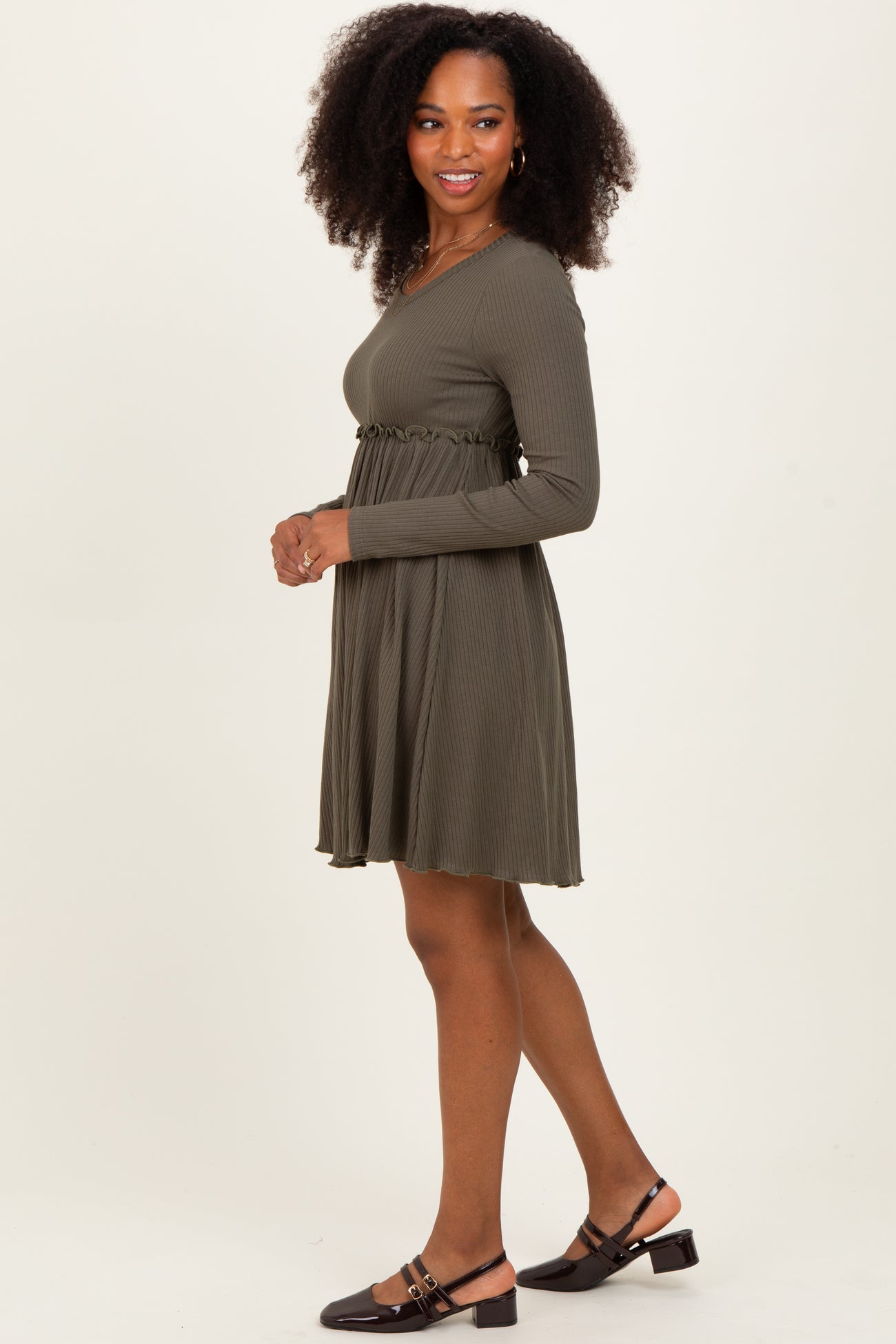 woman wearing an olive green ribbed long sleeve dress with a fitted waist and flared skirt, styled with brown flats