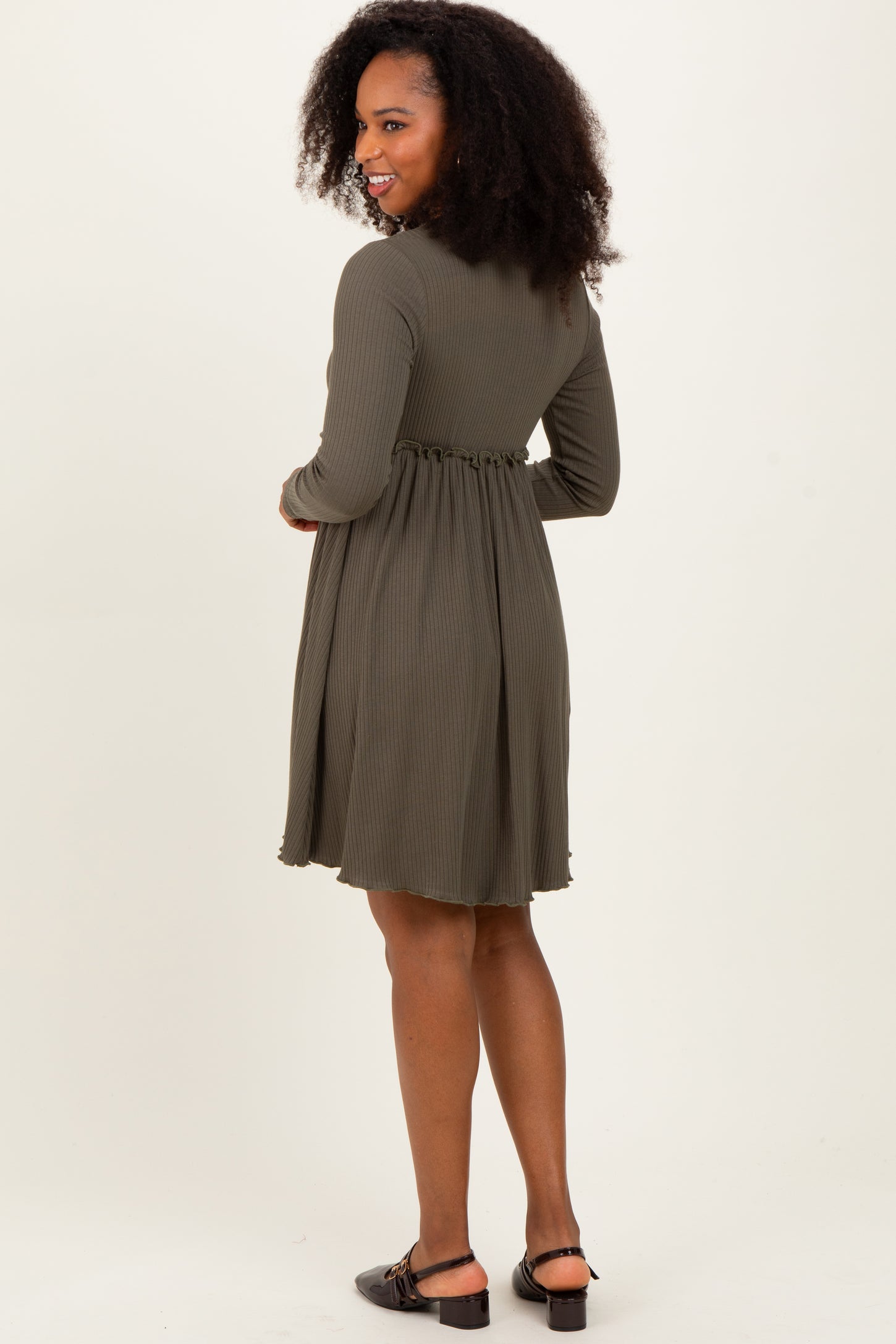 woman wearing an olive green long sleeve dress with a fitted waist and flared skirt, standing sideways