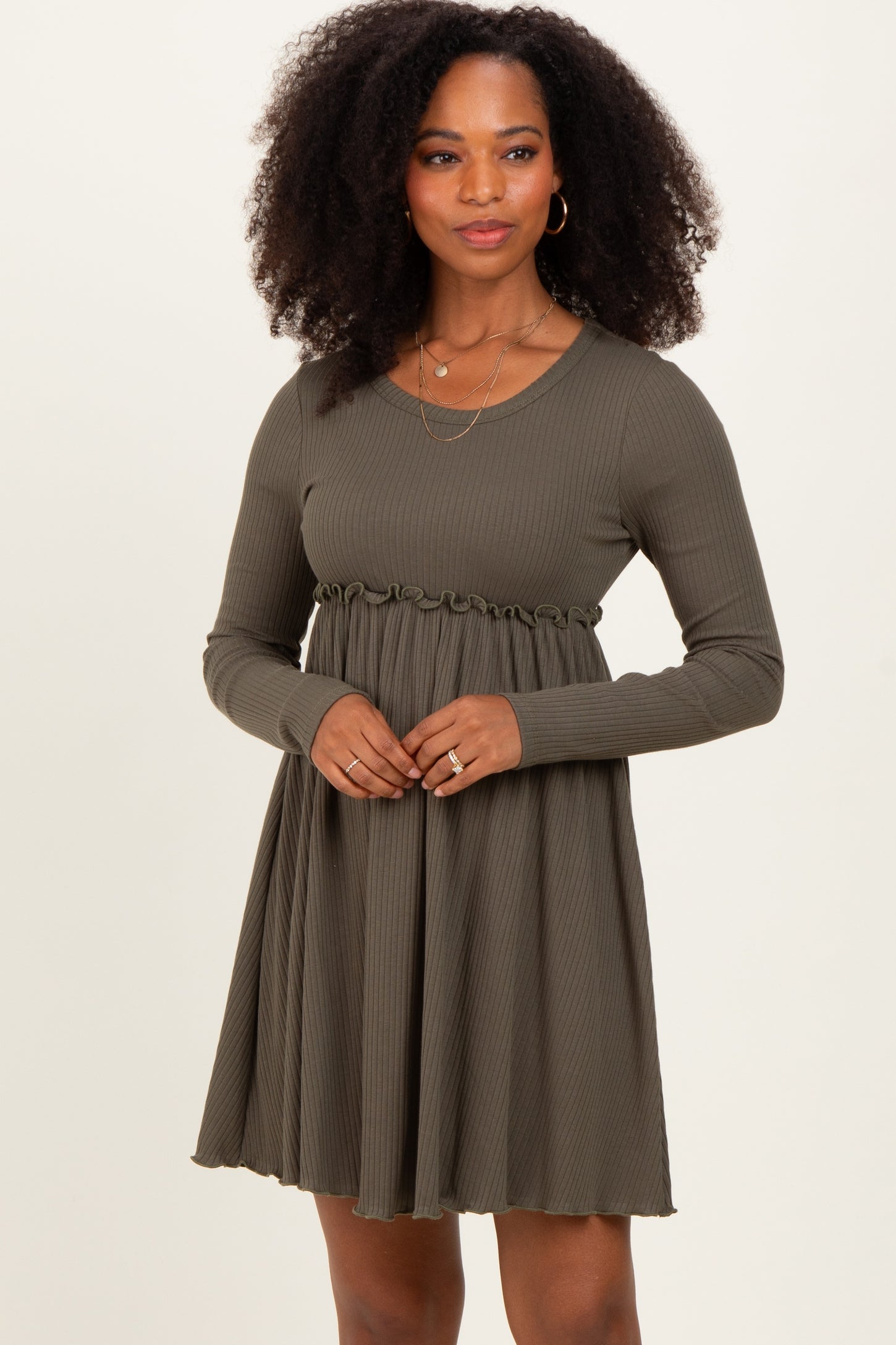woman wearing a dark olive green long sleeve dress with a cinched waist and flared skirt