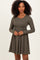 woman wearing a dark olive green long sleeve dress with a cinched waist and flared skirt