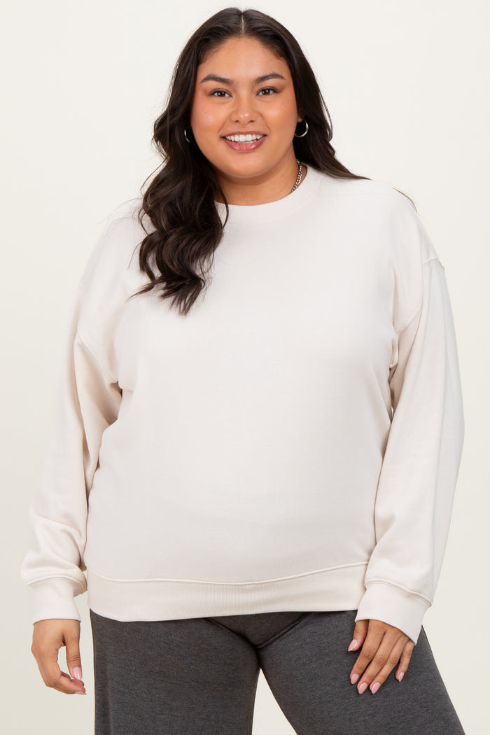 woman wearing a light beige plus size sweatshirt with long sleeves and a relaxed fit, paired with dark gray bottoms