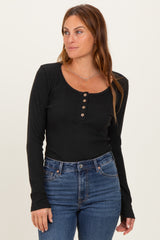 woman wearing a black long sleeve henley top with button details and dark blue skinny jeans