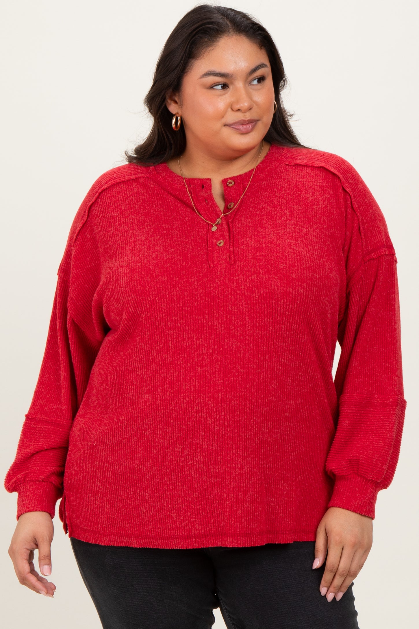 woman wearing a red plus size long sleeve henley top with button details and relaxed fit