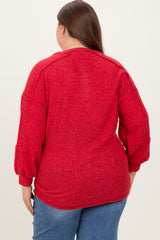 woman wearing a red plus size maternity sweater with balloon sleeves, showing the back view and relaxed fit