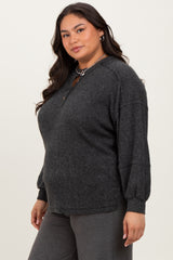 woman wearing a dark gray oversized knit top with long sleeves and a henley neckline