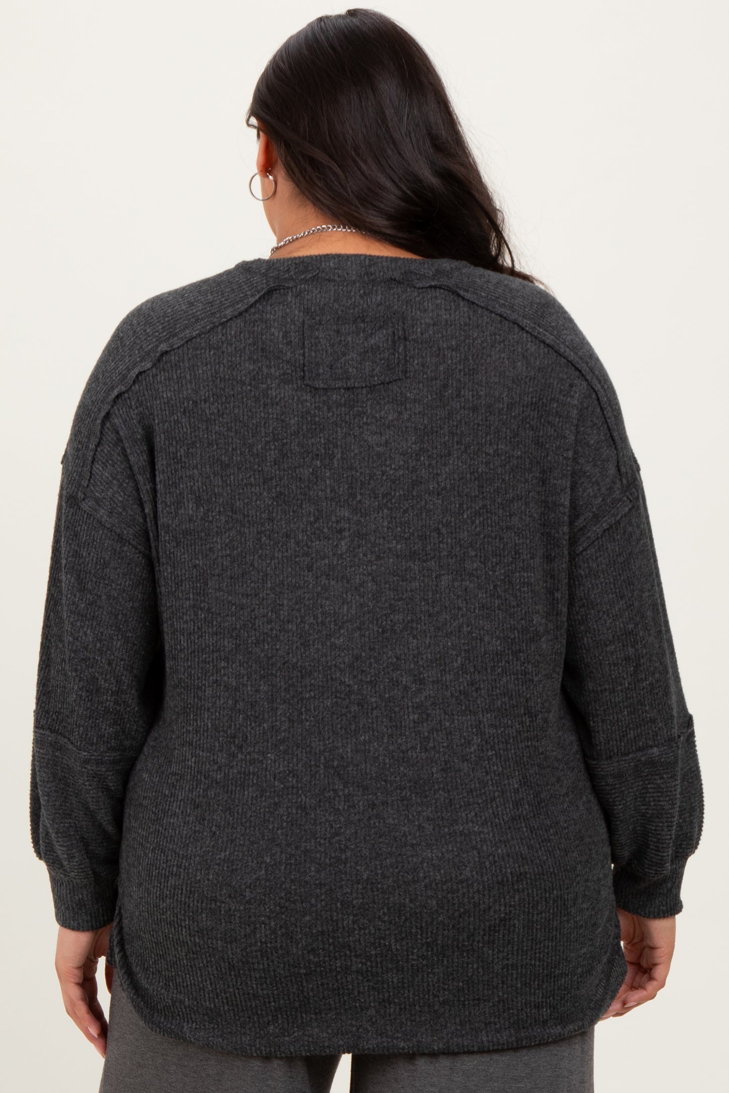 plus size woman wearing a dark gray oversized knit sweater, viewed from the back