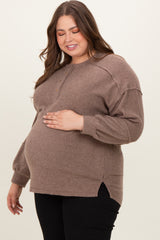 woman wearing a brown ribbed maternity sweater and gently holding her baby bump
