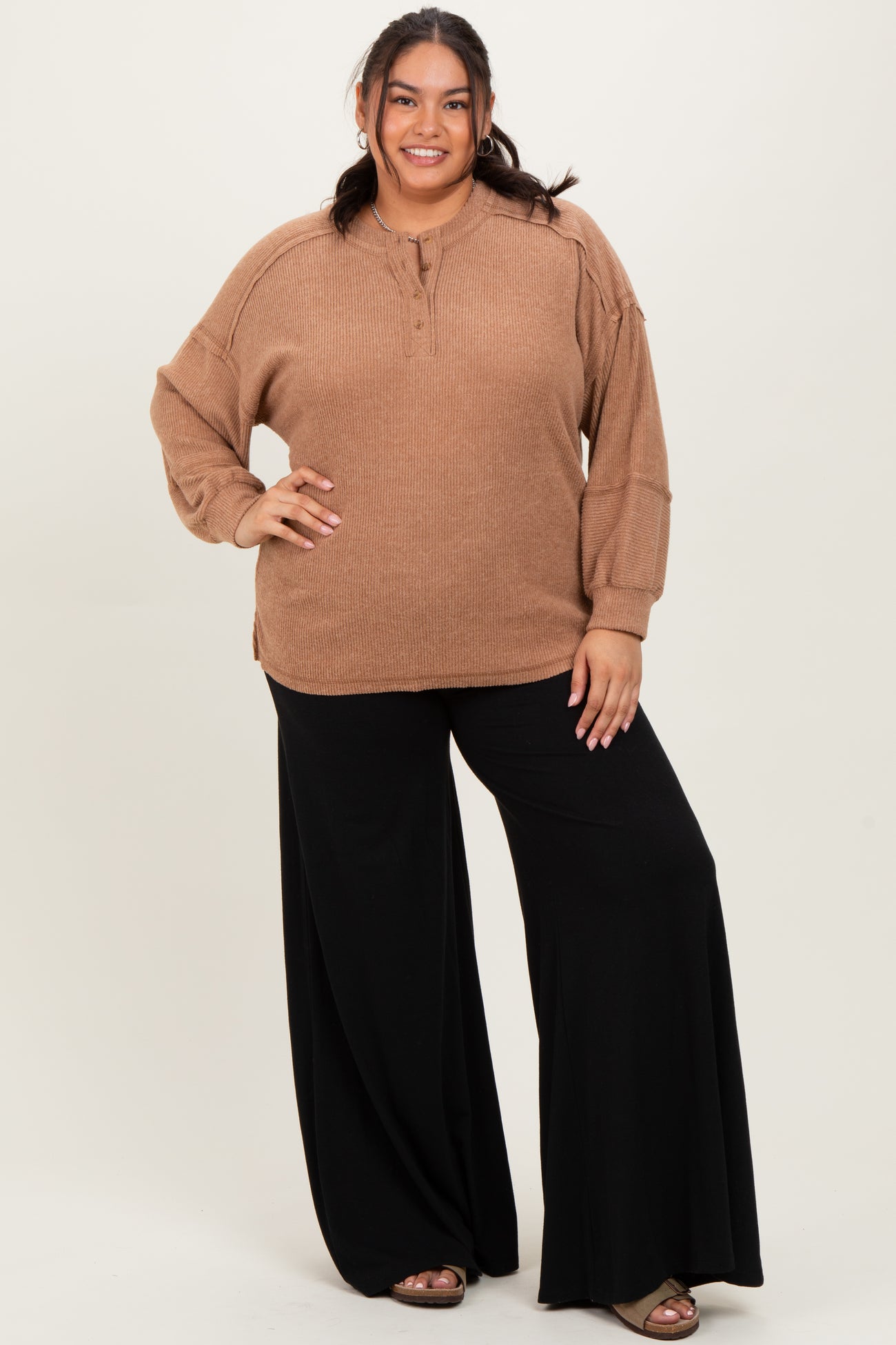 woman wearing a tan oversized sweater with buttons and black wide-leg pants