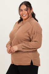 woman wearing a light brown plus size ribbed long sleeve top with a henley neckline and side slits