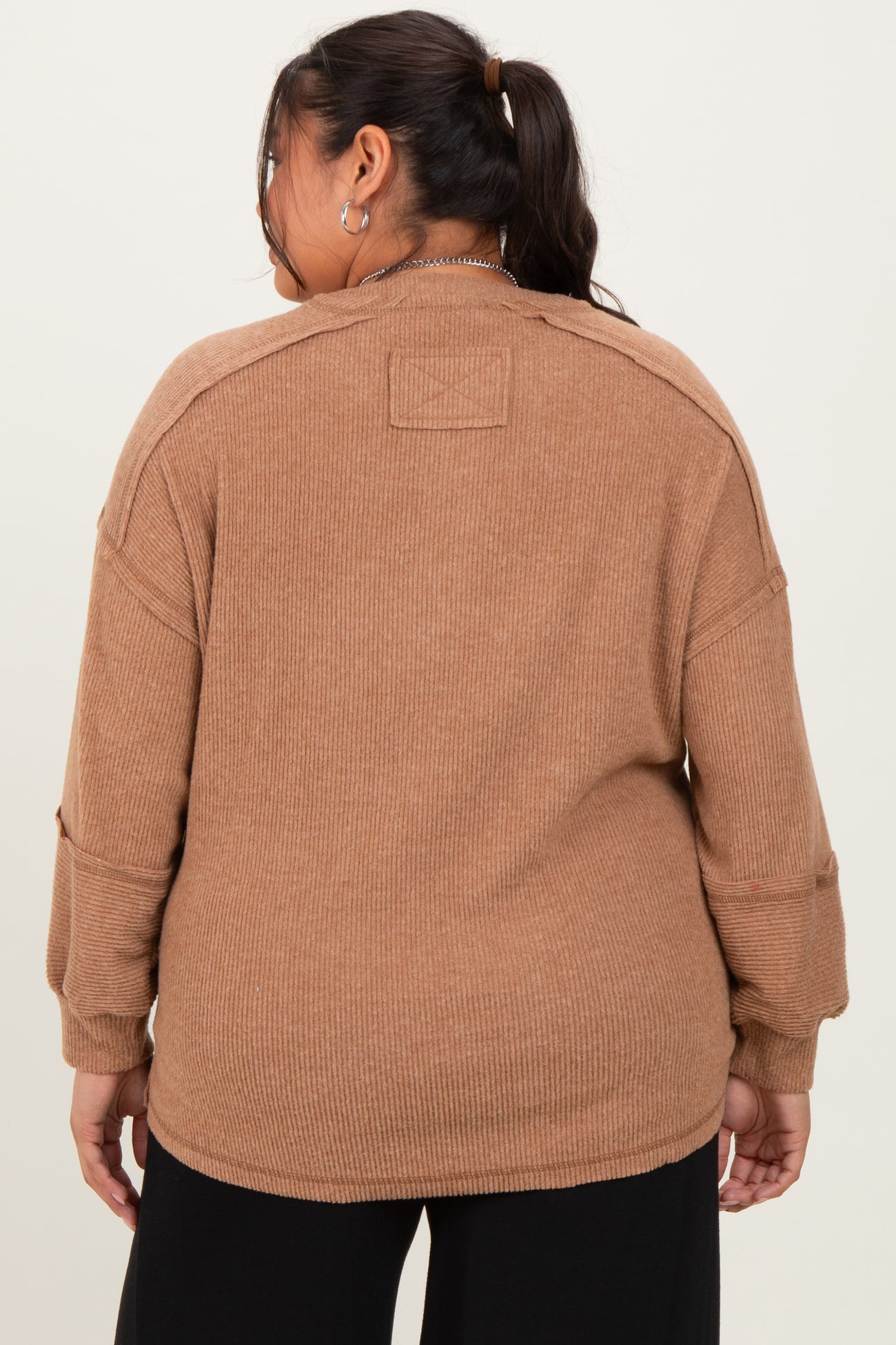 woman wearing a brown ribbed oversized sweater with dropped shoulders and a relaxed fit, viewed from the back