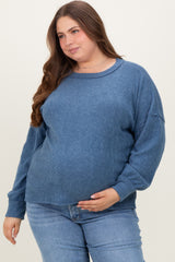 woman wearing a blue ribbed maternity sweater and holding her baby bump