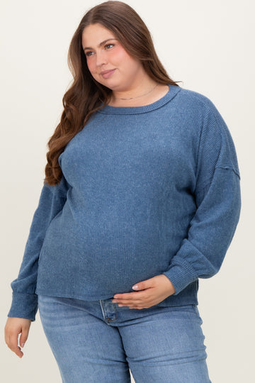 woman wearing a blue ribbed maternity sweater and holding her baby bump