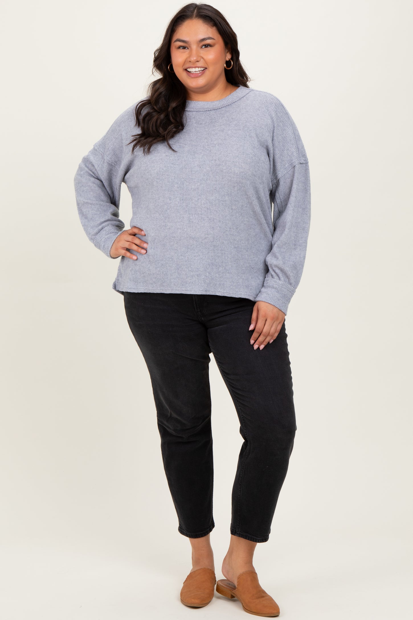 woman wearing a gray oversized sweater and black jeans with brown slip-on shoes