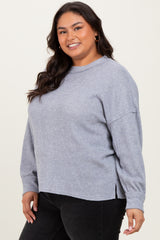 woman wearing a light grey ribbed plus size sweater with side slits and long sleeves, smiling at the camera
