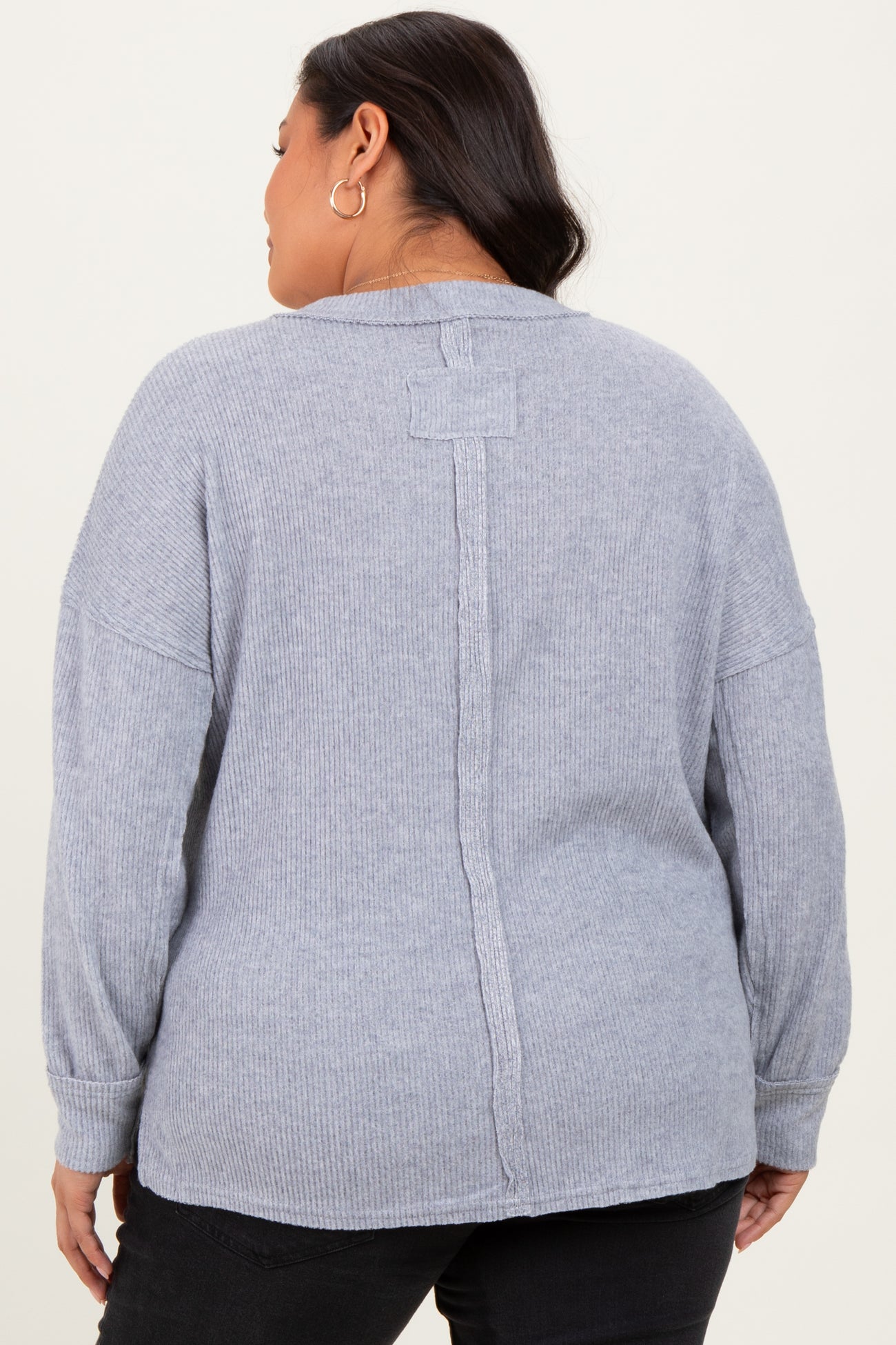plus size woman wearing a light gray ribbed sweater with a unique back seam detail and long sleeves