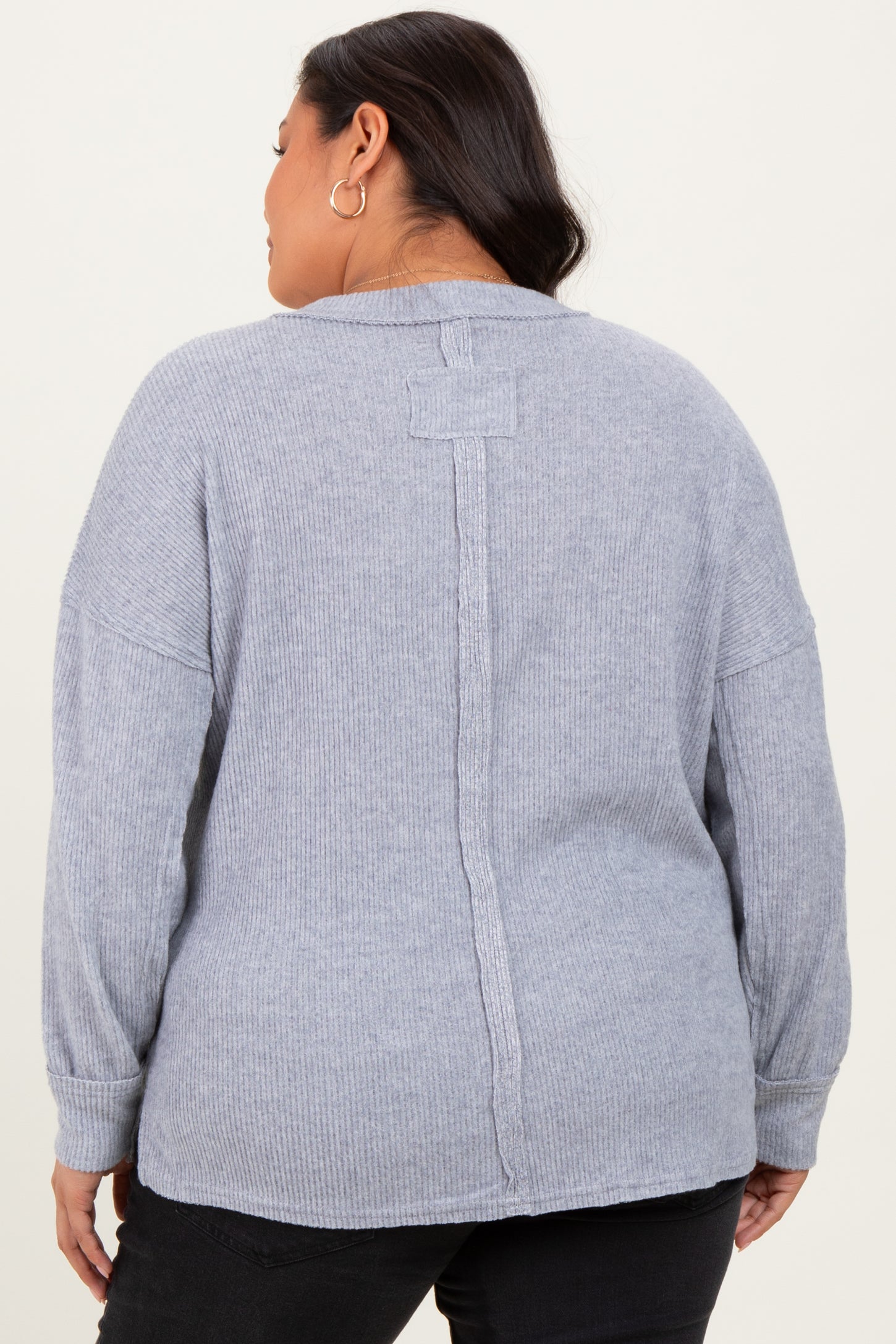 plus size woman wearing a light gray ribbed sweater with a unique back seam detail and long sleeves