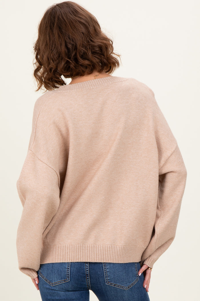 woman wearing a soft beige oversized sweater with a relaxed fit, styled with blue jeans, seen from the back