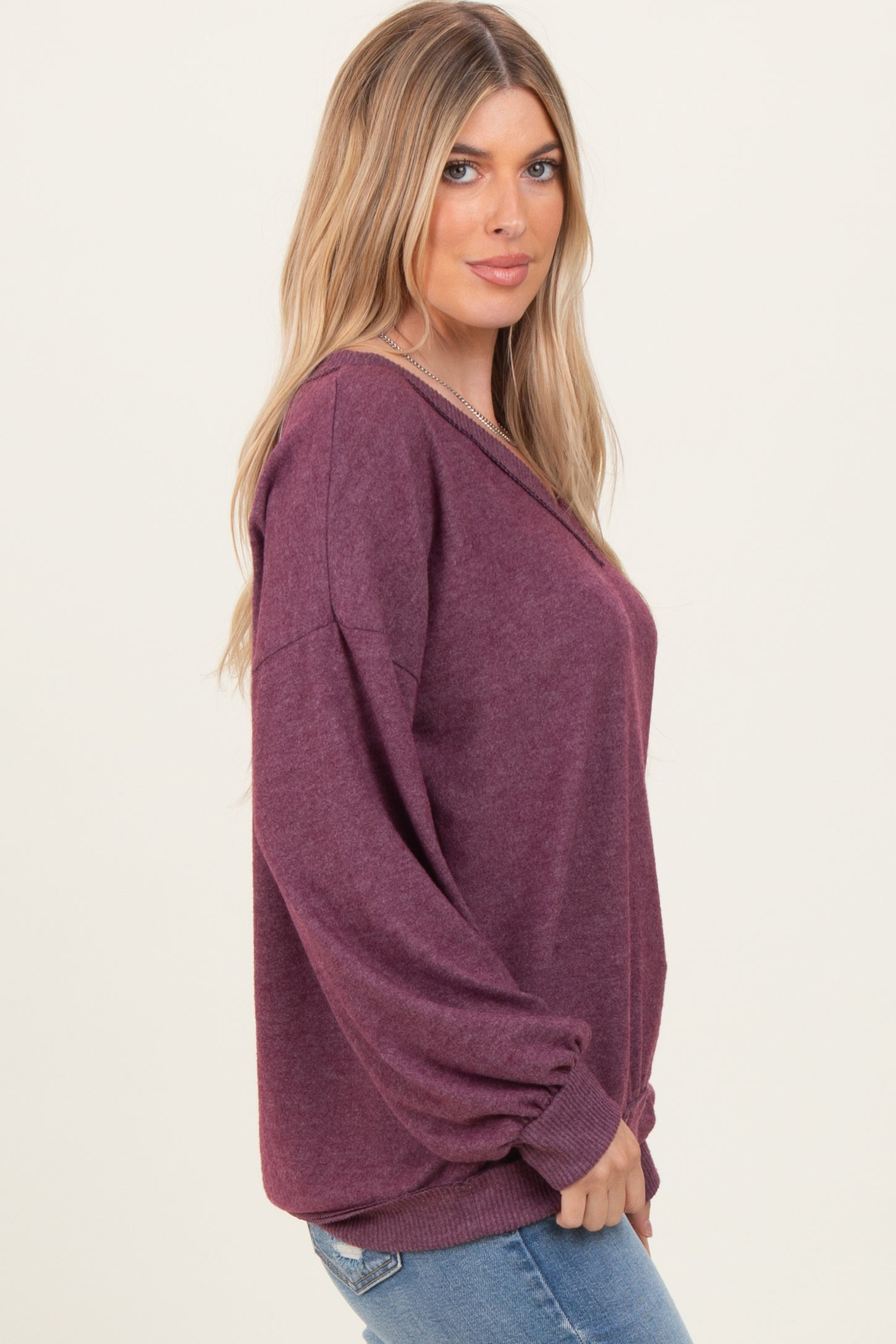 woman wearing a burgundy oversized sweater with balloon sleeves and a v-neck, styled with blue jeans