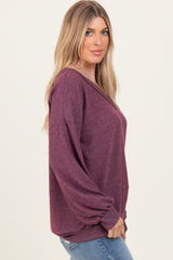 woman wearing a burgundy oversized sweater with balloon sleeves and a v-neck, styled with blue jeans