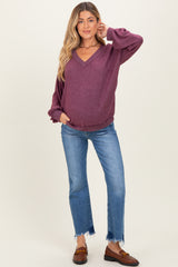 woman wearing a burgundy v-neck maternity sweater with puffed sleeves and blue distressed jeans