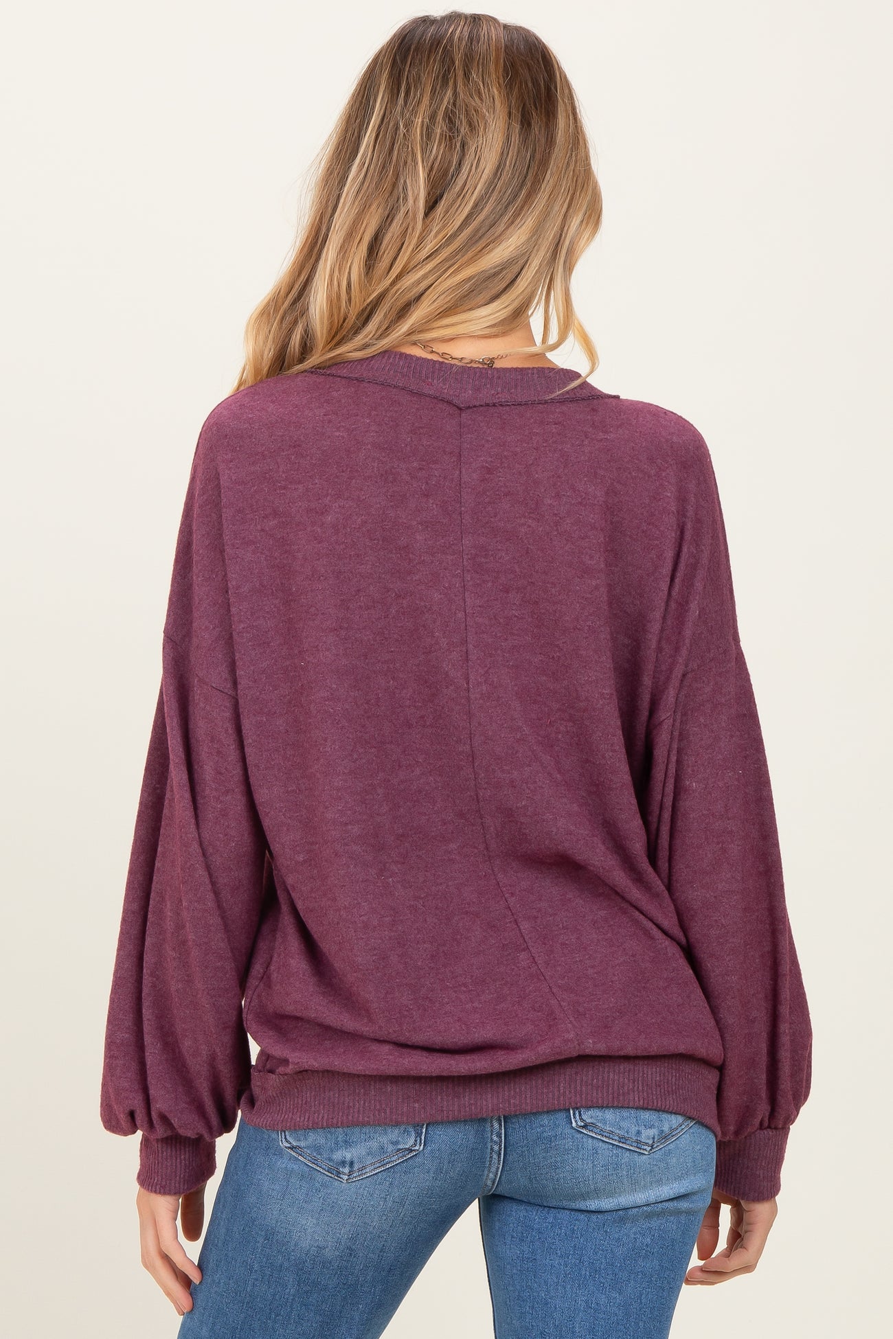 woman wearing a burgundy oversized maternity sweater with balloon sleeves, facing away from the camera