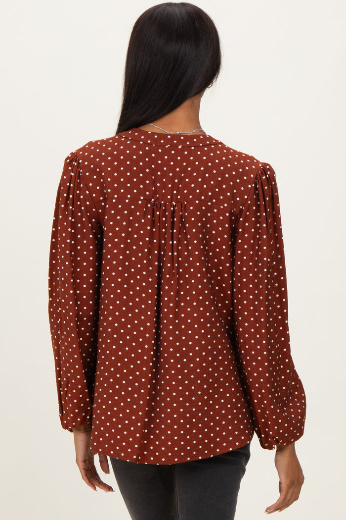 woman wearing a brown polka dot blouse with puff sleeves and a gathered back detail