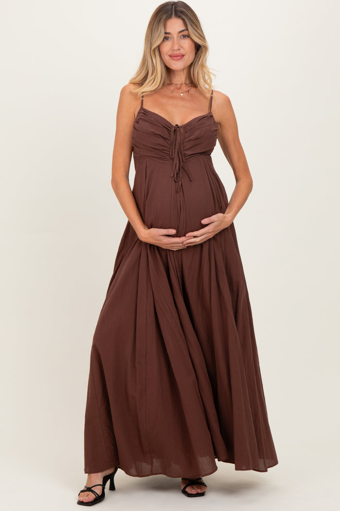 woman wearing a chocolate brown maternity maxi dress with a tie front, holding her baby bump