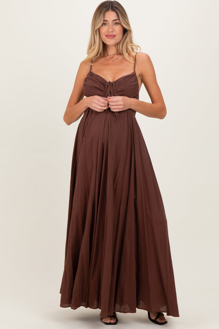 woman wearing a brown maternity maxi dress with adjustable straps and a tie front, showcasing her baby bump
