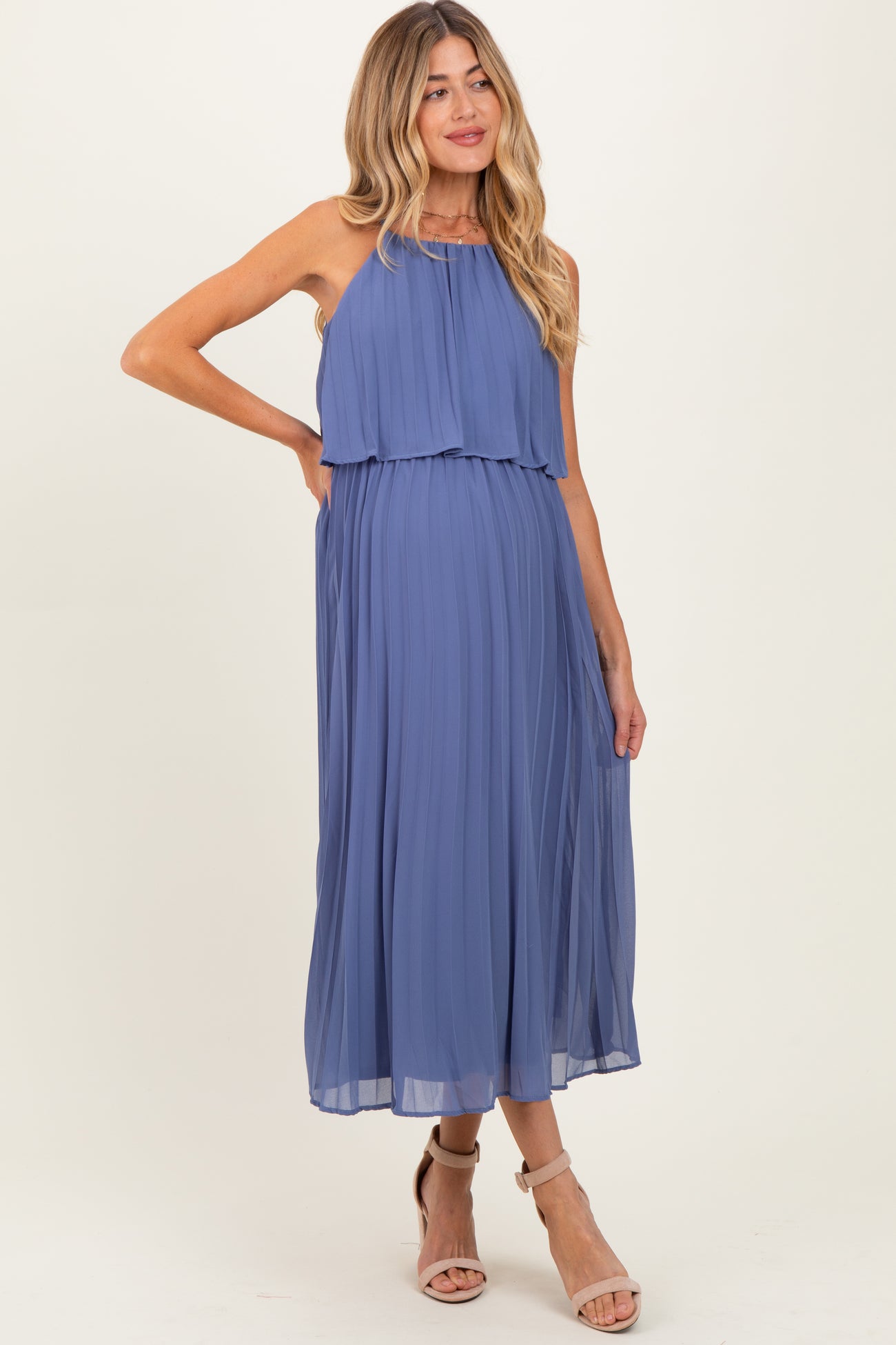 woman wearing a pleated blue maternity dress with a flowing top layer and a visible baby bump