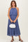 woman wearing a pleated blue maxi dress with a halter neck and a white fluffy handbag