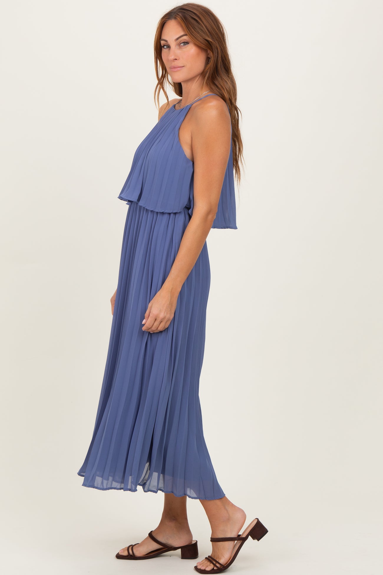 woman wearing a sleeveless lavender pleated maxi dress with layered bodice and strappy sandals