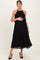 woman wearing a black pleated maternity dress and holding her baby bump